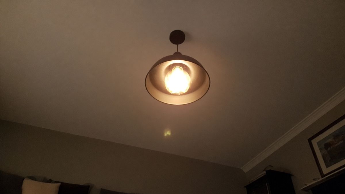 A ceiling pendant light glowing in a dim living room