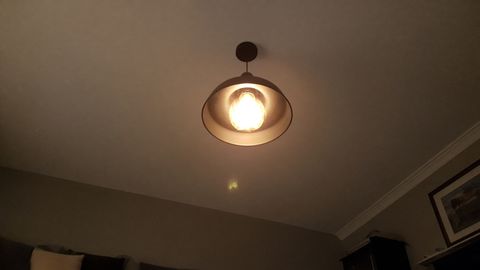 A ceiling pendant light glowing in a dim living room